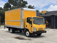 A bright yellow box truck is parked in front of a building with a