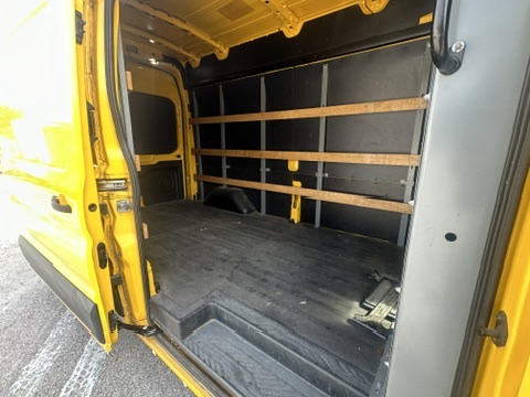 Interior of a yellow cargo van with wooden shelving and a black floor.