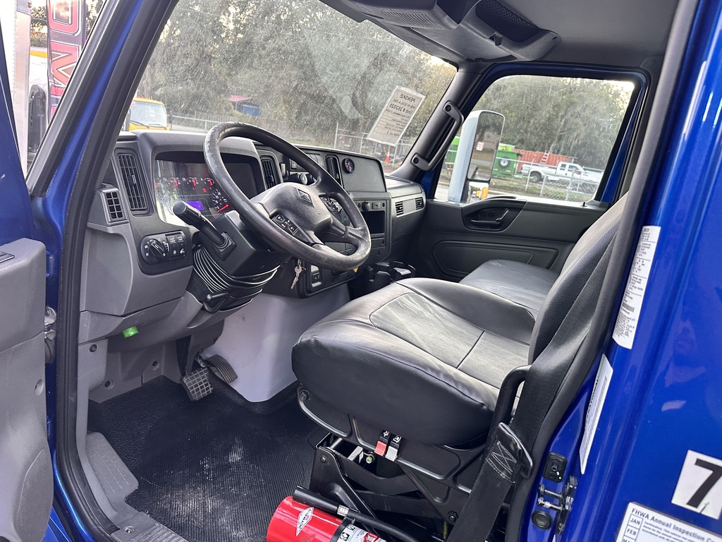 Interior view of a blue truck cab, showing driver's seat, steering wheel, and dashboard.