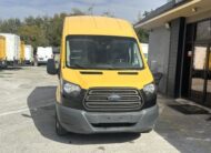 Yellow Ford Transit van parked in front of a building.