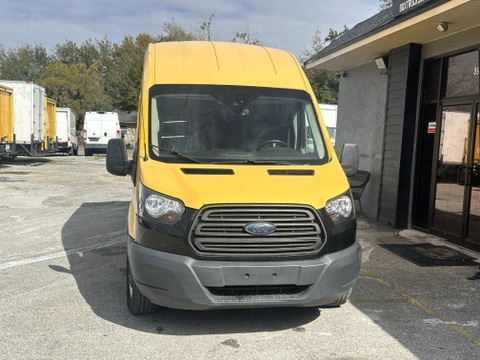 Yellow Ford Transit van parked in front of a building.