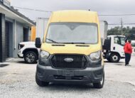 Yellow Ford Transit van parked outdoors with other vehicles