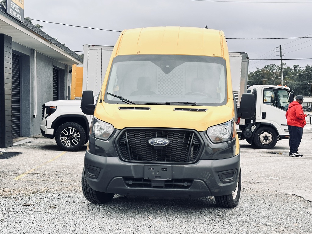 Yellow Ford Transit van parked outdoors with other vehicles