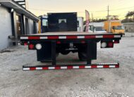 Rear view of a black flatbed truck with red and white reflective tape.