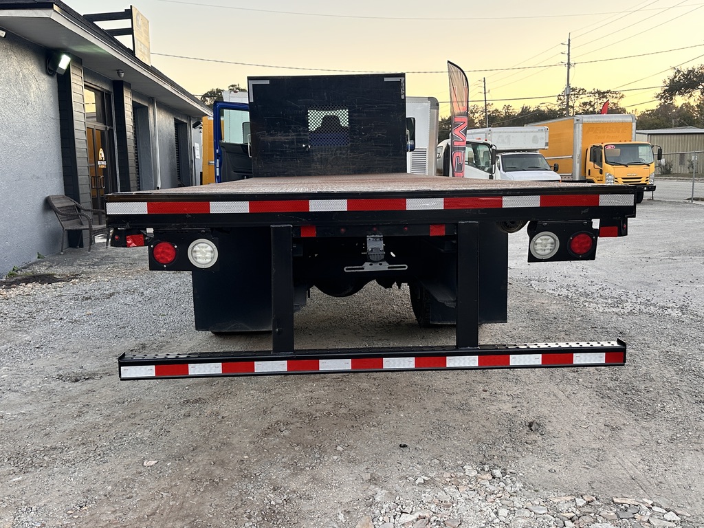 Rear view of a black flatbed truck with red and white reflective tape.