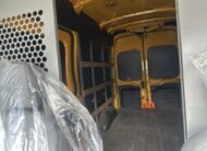 Interior view of a yellow cargo van with shelving and protective wrap