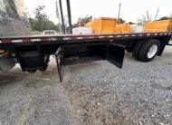 Flatbed truck with open storage compartments and dual rear wheels