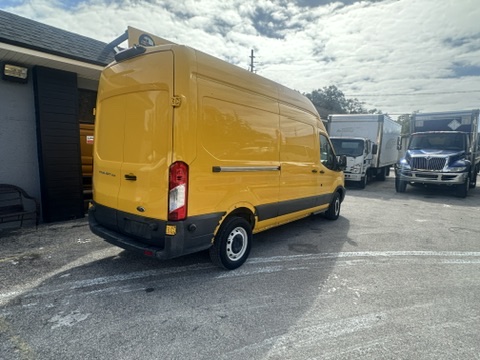 Bright yellow Ford Transit van parked outdoors, ready for delivery services.