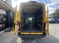 Rear view of an empty yellow Ford Transit cargo van with doors open.