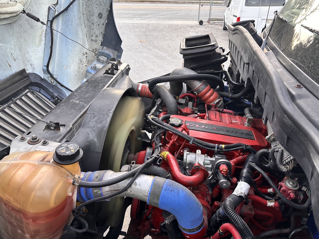 Close-up of a Cummins diesel engine in a semi-truck, showing red engine block and hoses.