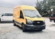 Yellow Ford Transit cargo van parked on gravel lot