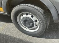 Close-up of a Firestone van tire on a gray rim, parked on asphalt.