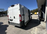 White Ram ProMaster van parked next to a building with side door open