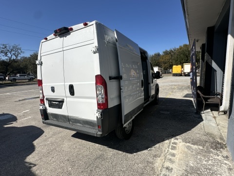 White Ram ProMaster van parked next to a building with side door open