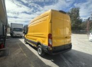 Yellow Ford Transit van parked outdoors on a sunny day.