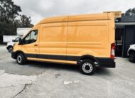 Bright yellow Ford Transit van parked on a paved lot.
