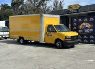 Yellow Penske box truck parked outside a sales and rentals business