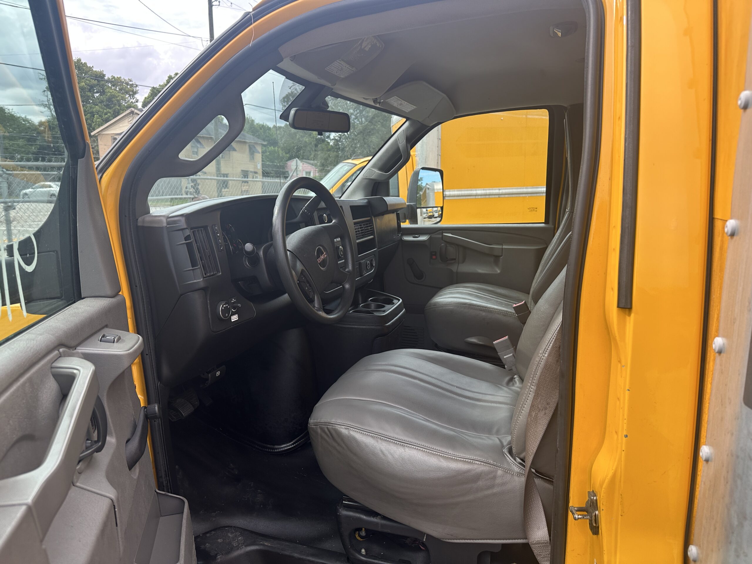 Interior view of a 2020 GMC Savana 3500 box truck, showing driver and passenger seats.