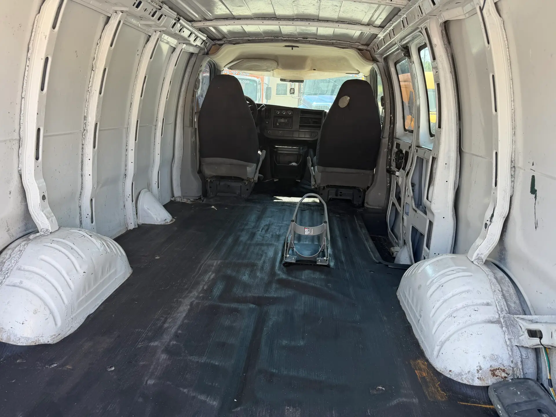 Interior of a 2009 Chevy G2500 cargo van, showing empty cargo space and front seats.