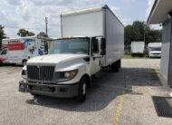 White International box truck parked in a lot with U-Haul trucks.