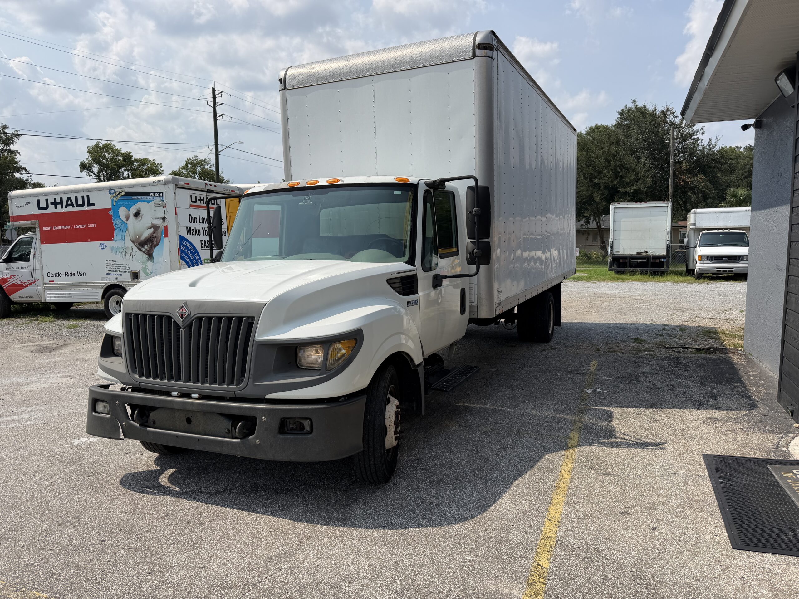 White International box truck parked in a lot with U-Haul trucks.