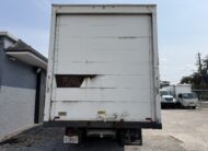 Rear view of a white box truck with a damaged panel, license plate XEG 682