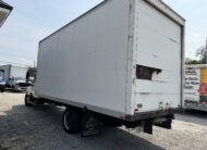White box truck with damage on the rear door, parked outdoors.