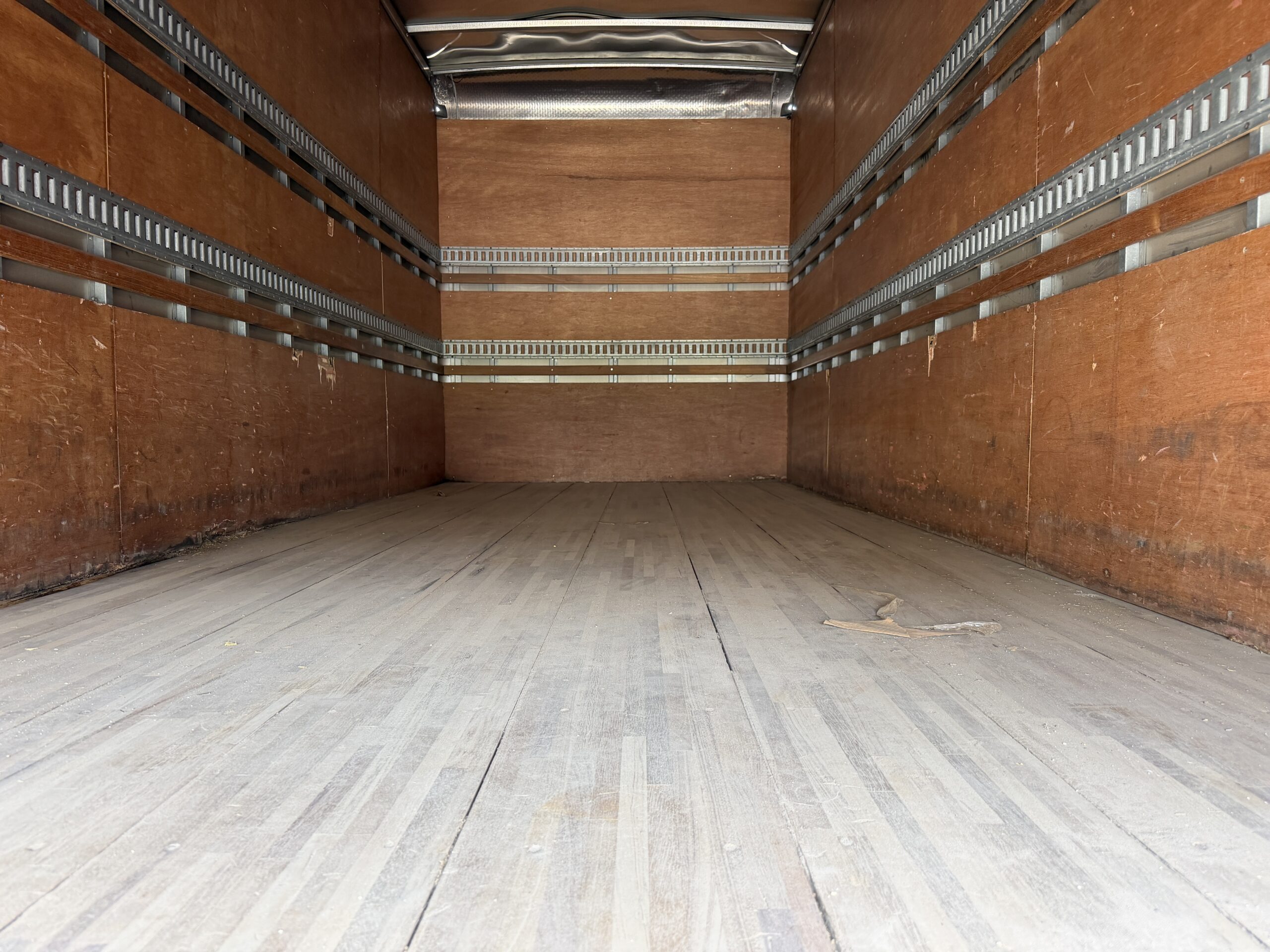 Interior of an empty truck cargo bay with wooden floor and walls.