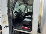 Interior view of a white box truck cab, showing seats, steering wheel, and fire extinguisher.