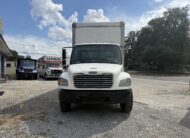 2007 Freightliner M2 26ft box truck front view, U-Haul trucks nearby.