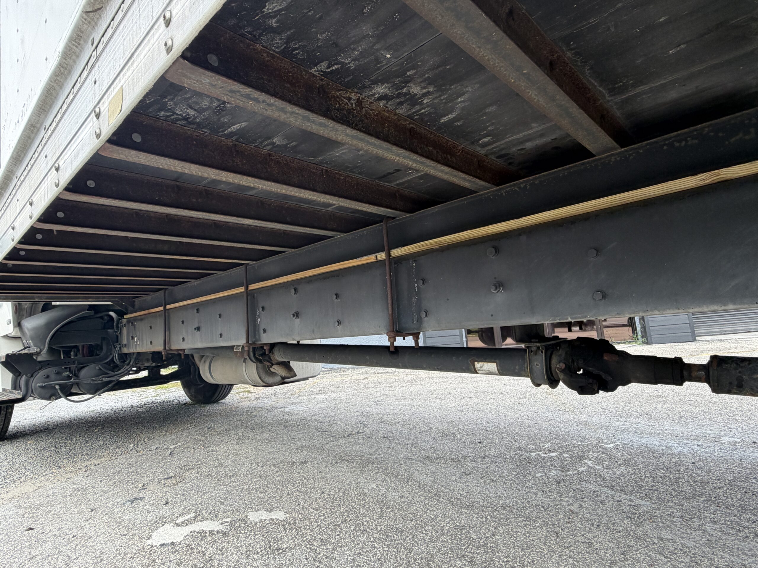 2007 Freightliner M2 box truck undercarriage with driveshaft and liftgate components.