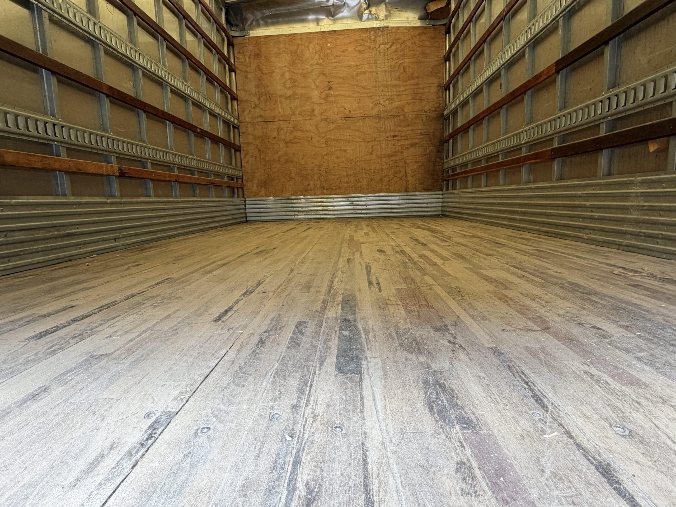 Interior of a clean, empty 16ft Isuzu NQR diesel box truck cargo area.