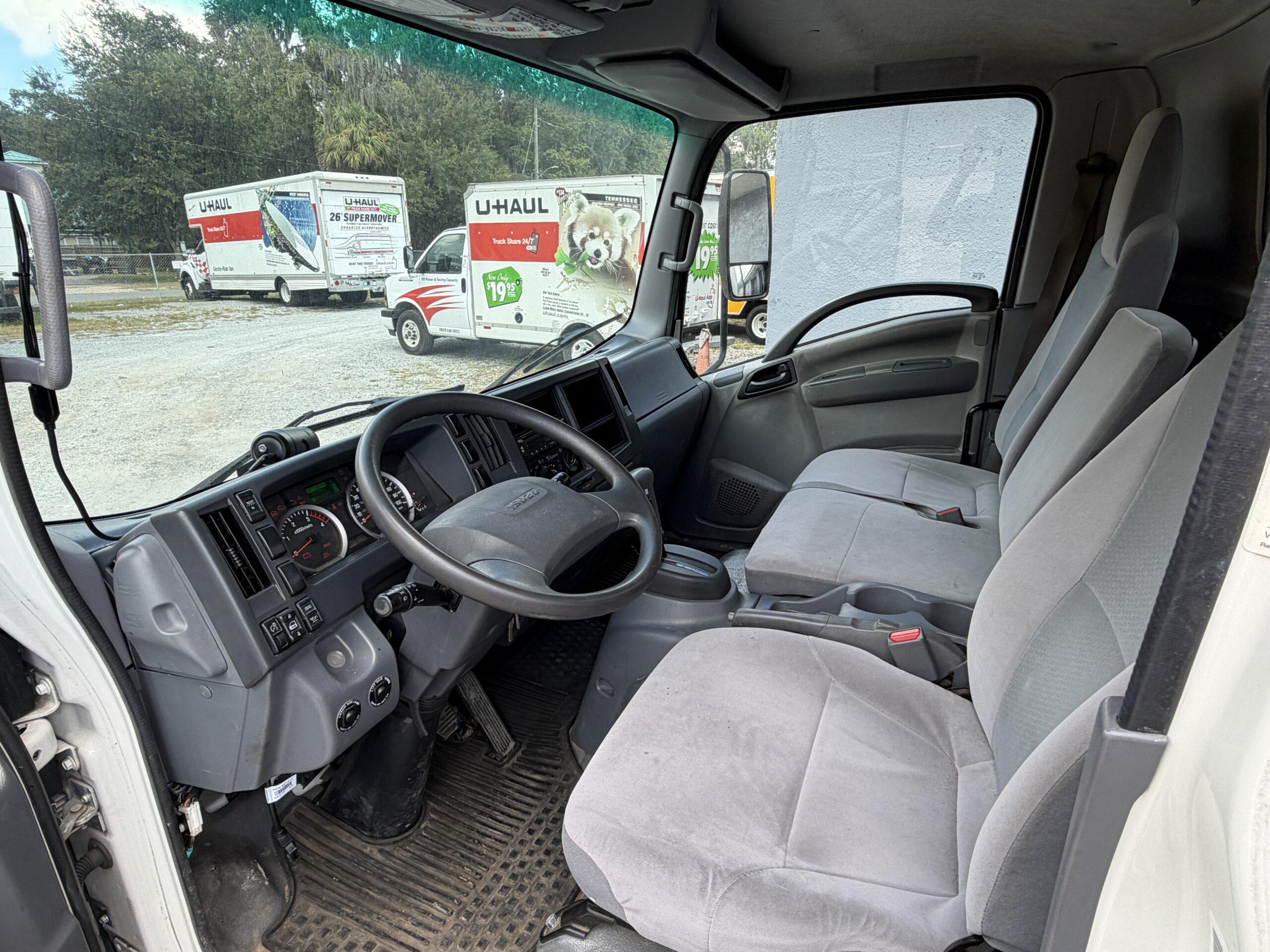 Interior of a 2019 Isuzu NQR 16ft. diesel box truck, showing the driver's seat and dashboard.