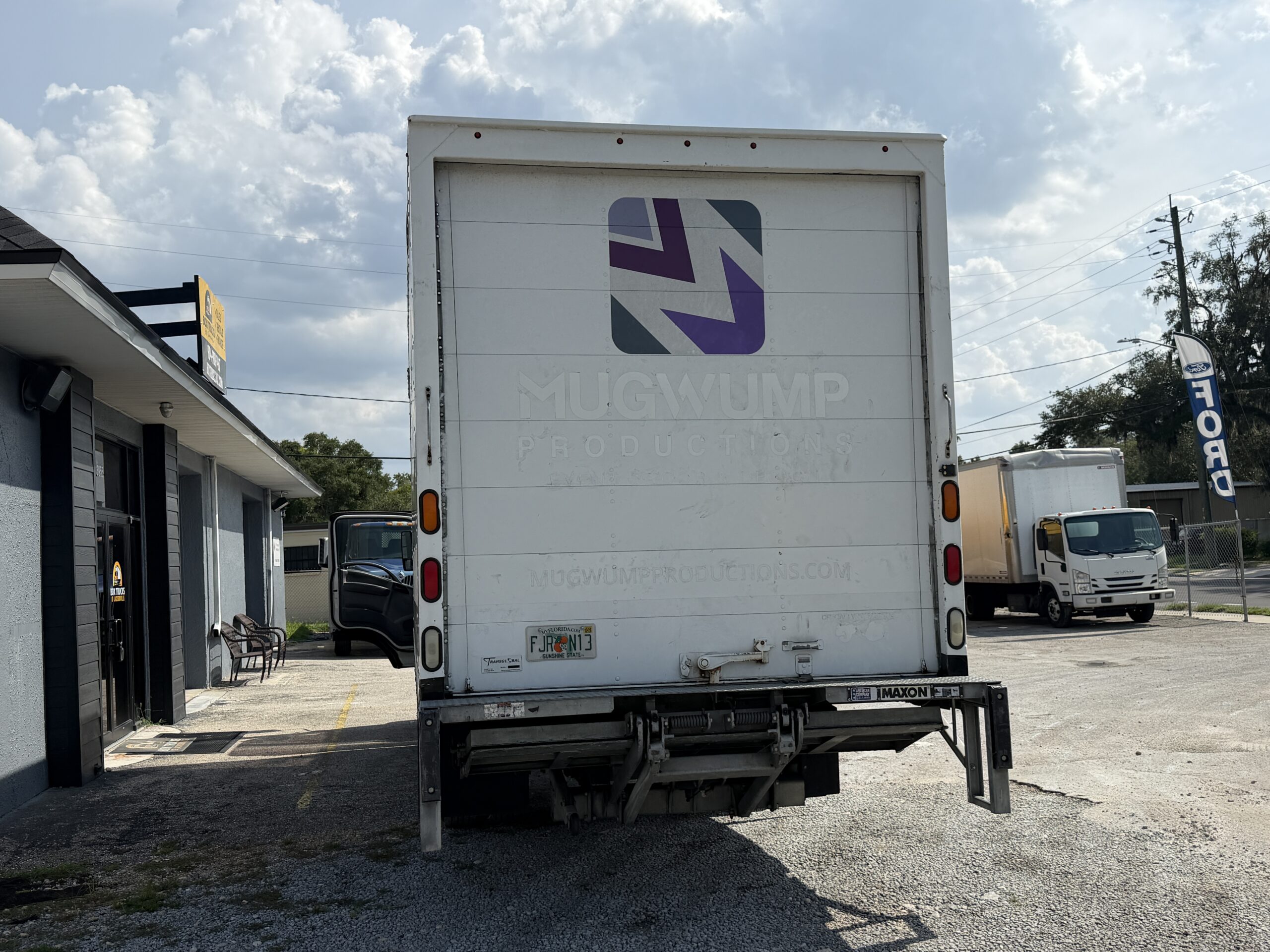 Rear view of a white 2020 Isuzu NRR 20ft. box truck with a liftgate.