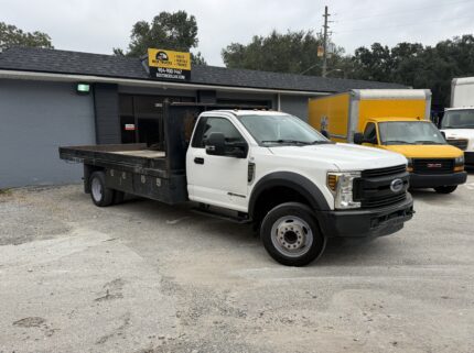 2019 Ford F-550 stake body truck parked outside a dealership