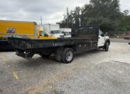 2019 Ford F-550 stake body truck with flatbed, parked outdoors.