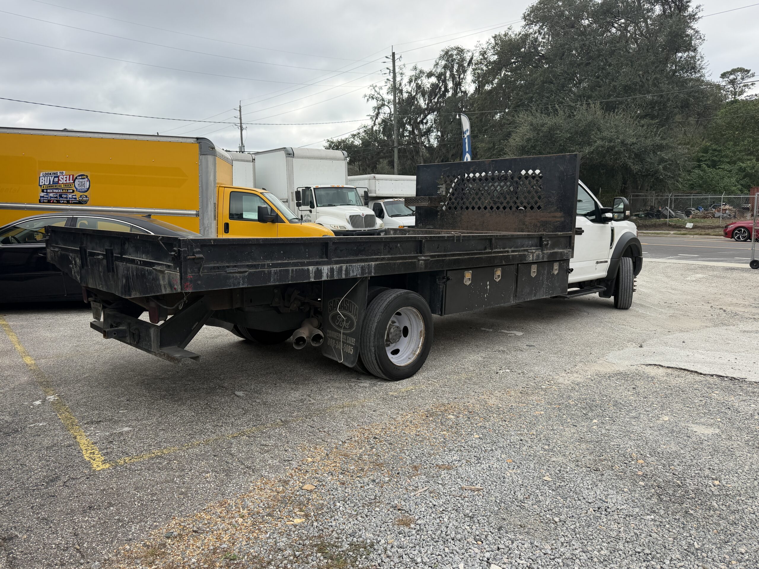2019 Ford F-550 stake body truck with flatbed, parked outdoors.