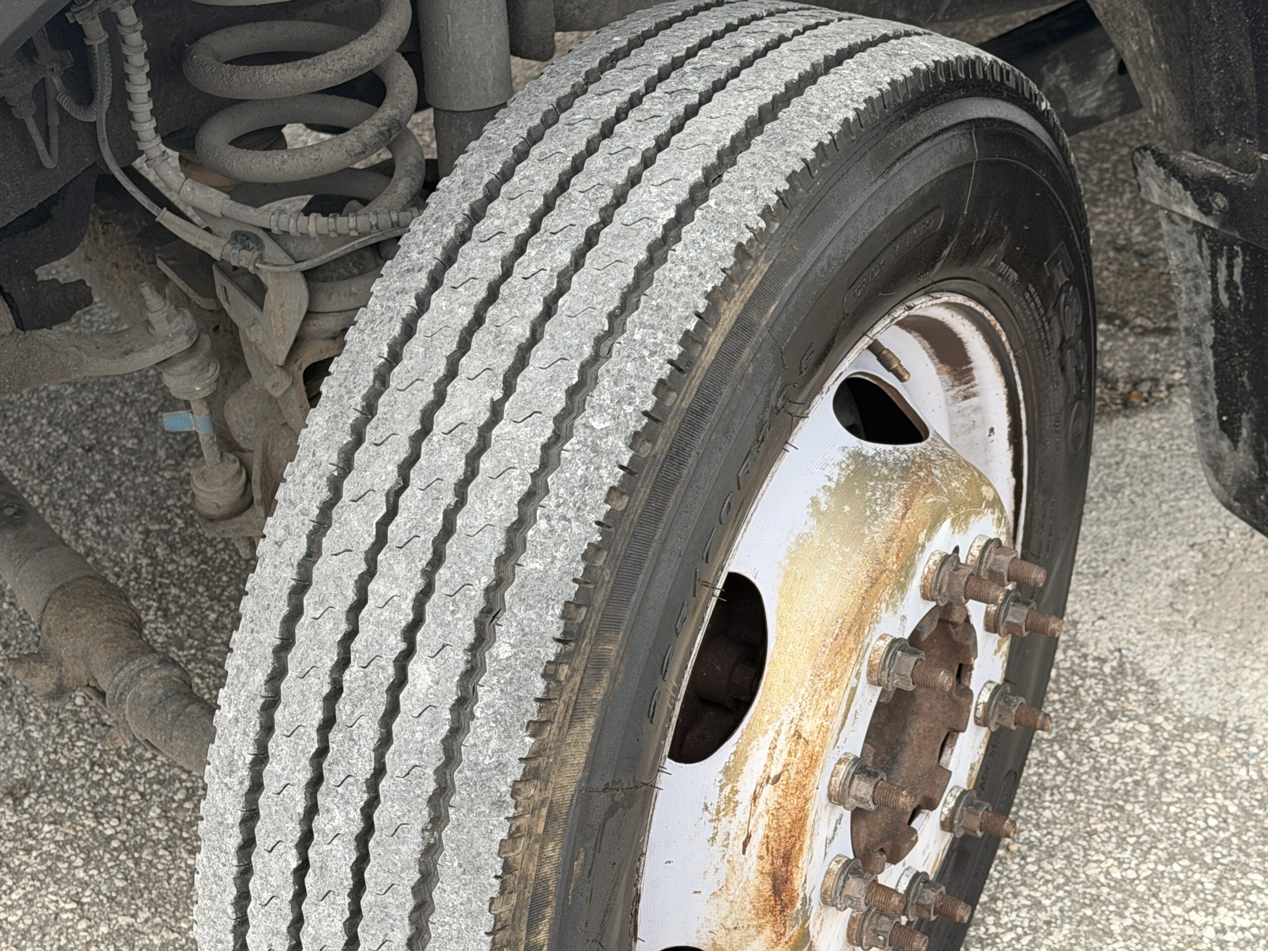 Close-up of a 2019 Ford F-550 stake body truck tire and rusty wheel